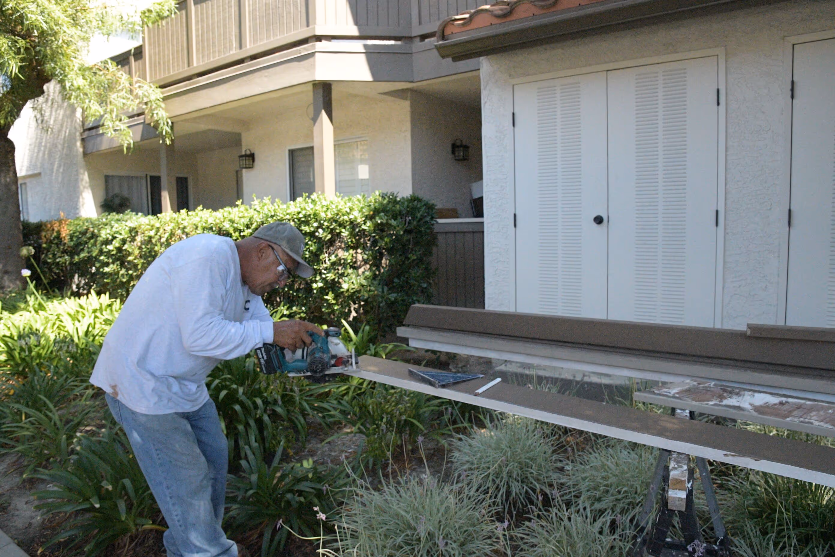 A man is painting a bench in front of a building.