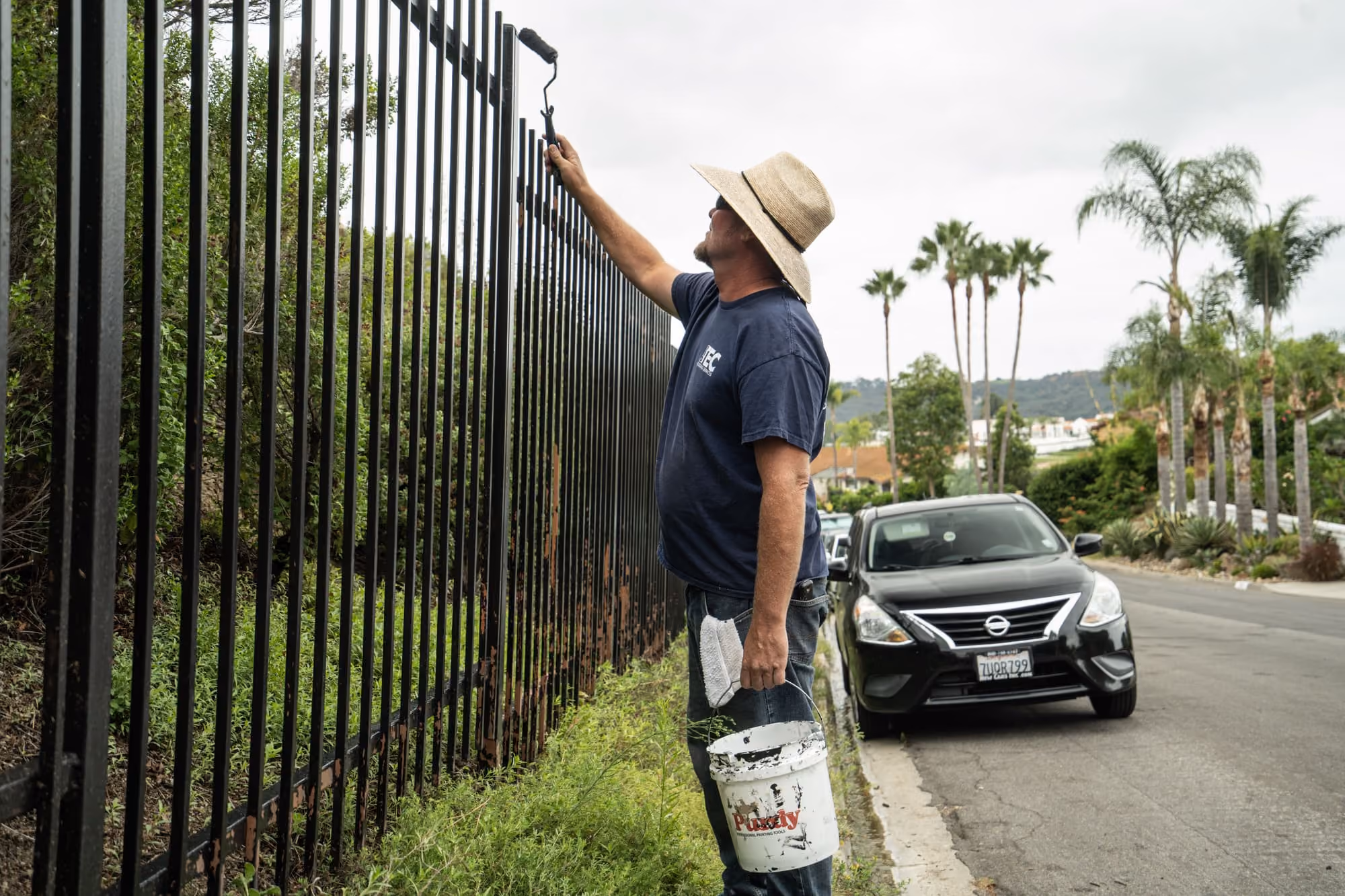protec worker painting a fence