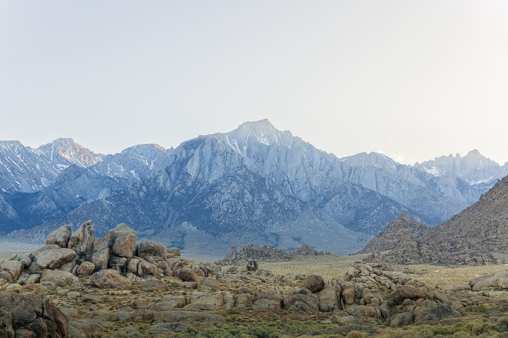 Looking across the rocky landscape of Alabama Hills toward the Sierra Nevada Mountains lit by the last rays of sunlight in the evening