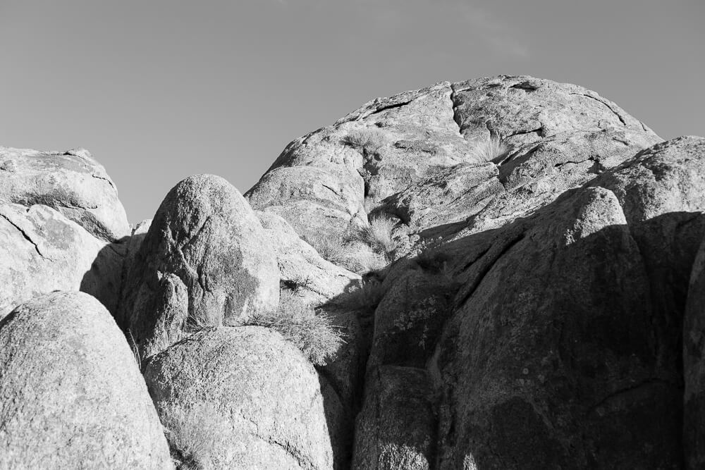 A black and white image of a large set of boulders with harsh shadows across them