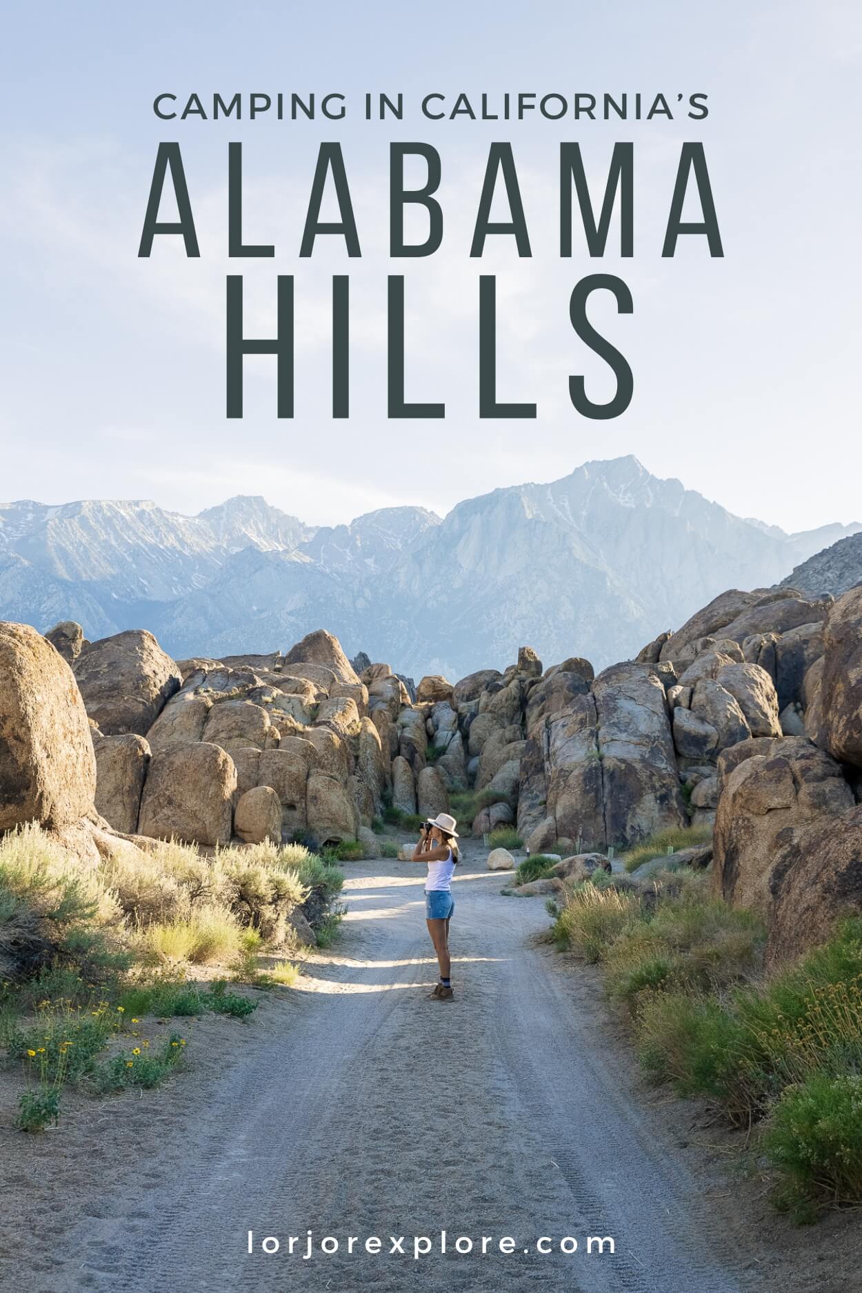 A woman standing on a dirt road taking a photo with large boulders and mountains in the background with text overlay that says "Camping in California's Alabama Hills"