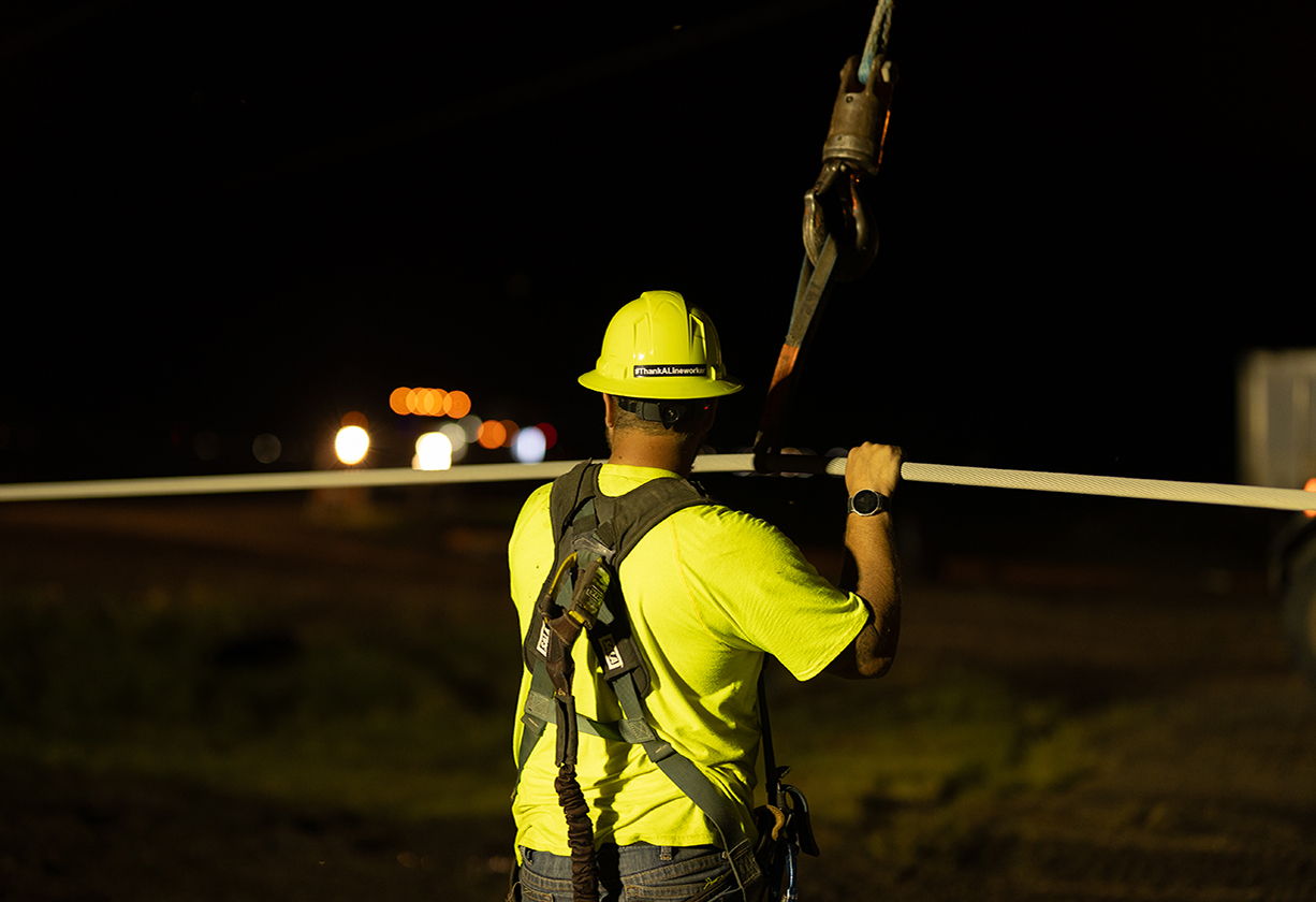 Minnkota lineworker in a harness working at night
