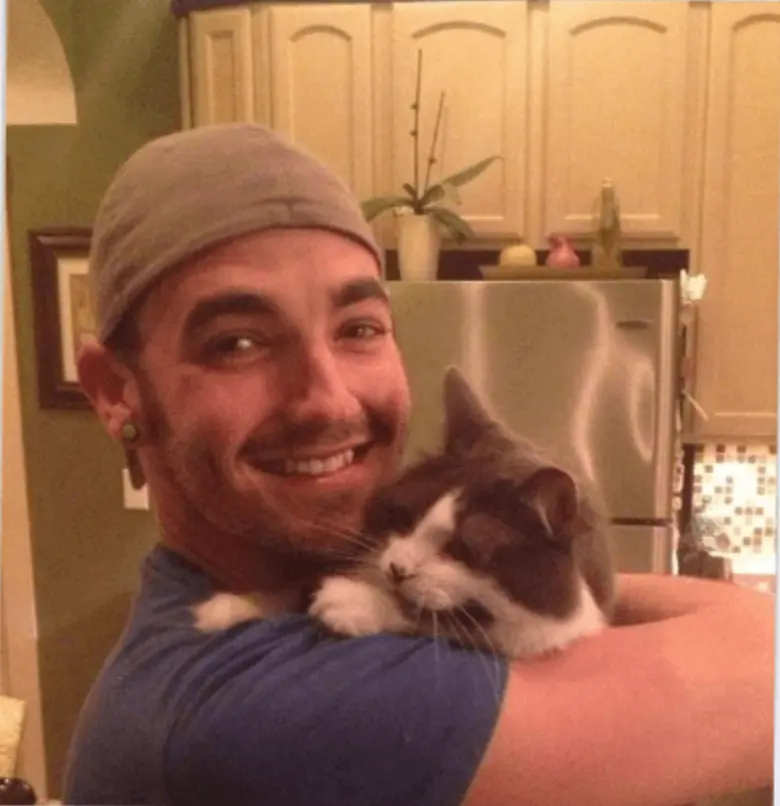 a man cuddles a gray and white cat