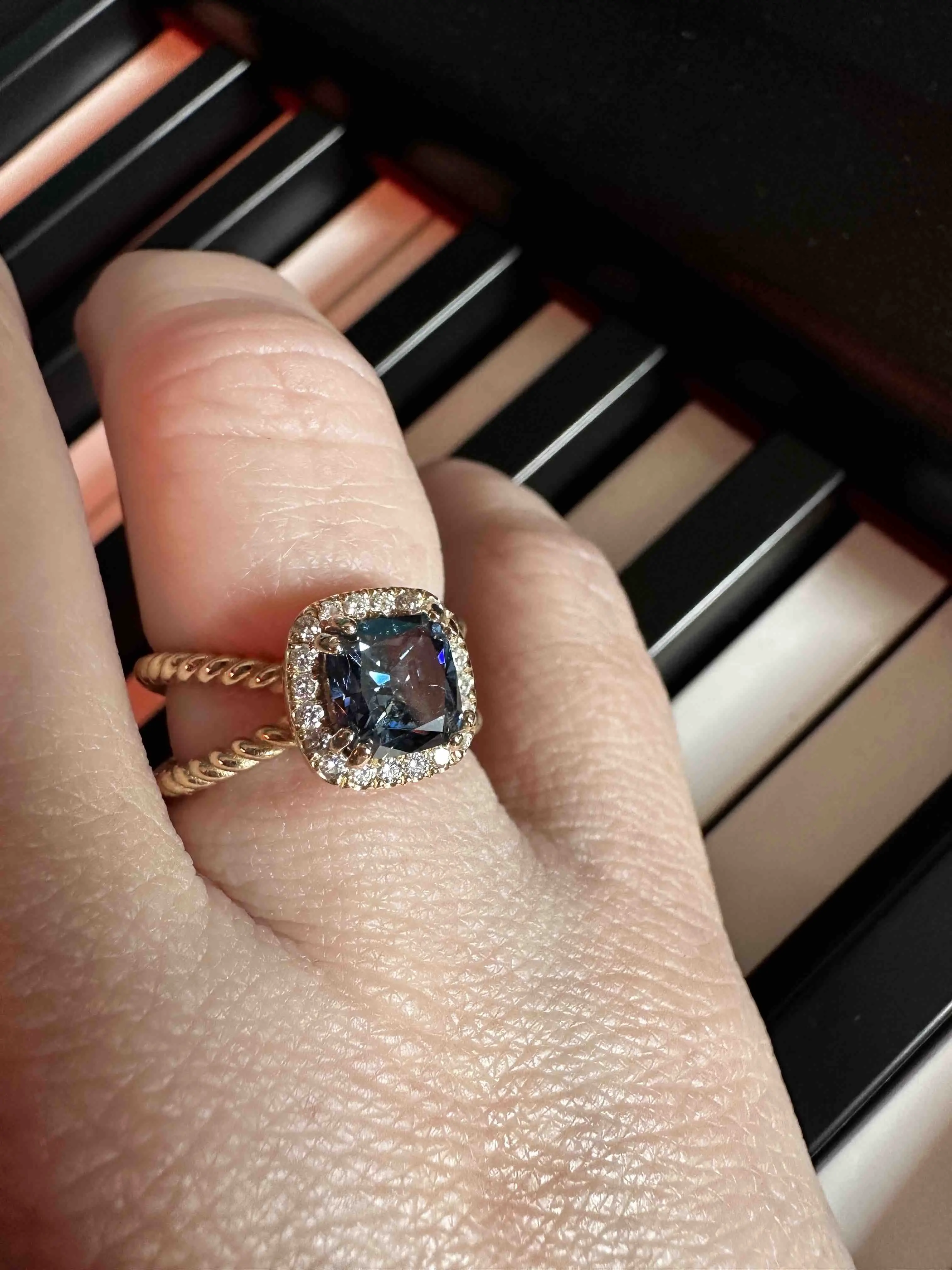 blue diamond set in gold ring on finger