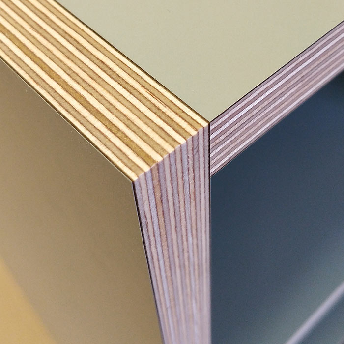Close-up of a wooden plywood corner with visible layered edges and smooth, painted surfaces.