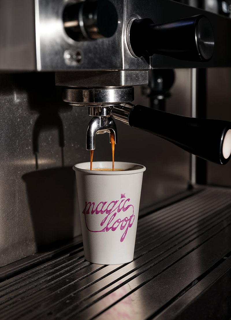 Mockup of Magic Loop logo stamped onto a coffee cup with espresso shots being poured into it.