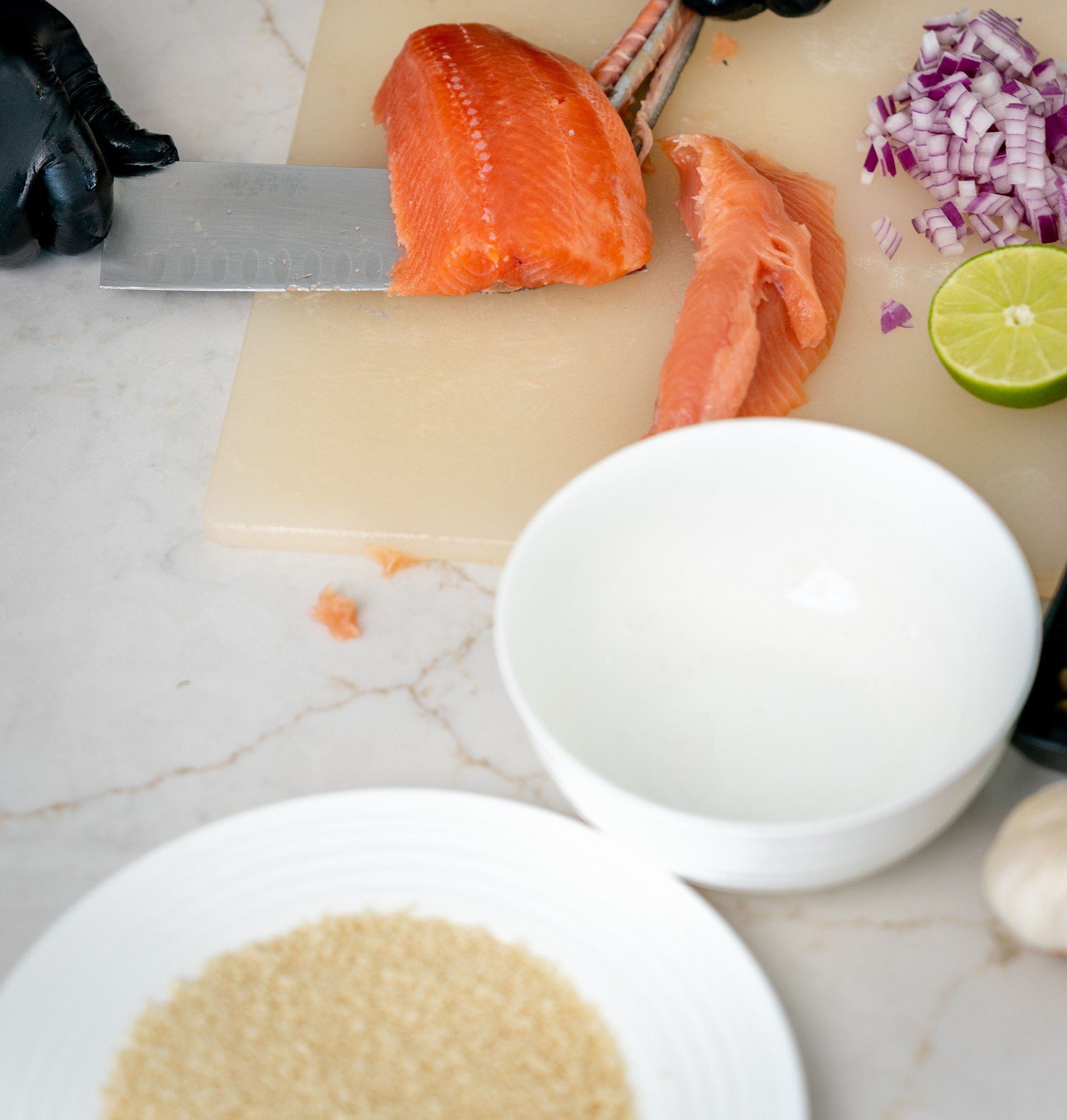 Removing the skin from a salmon fillet with a long knife on a cutting board