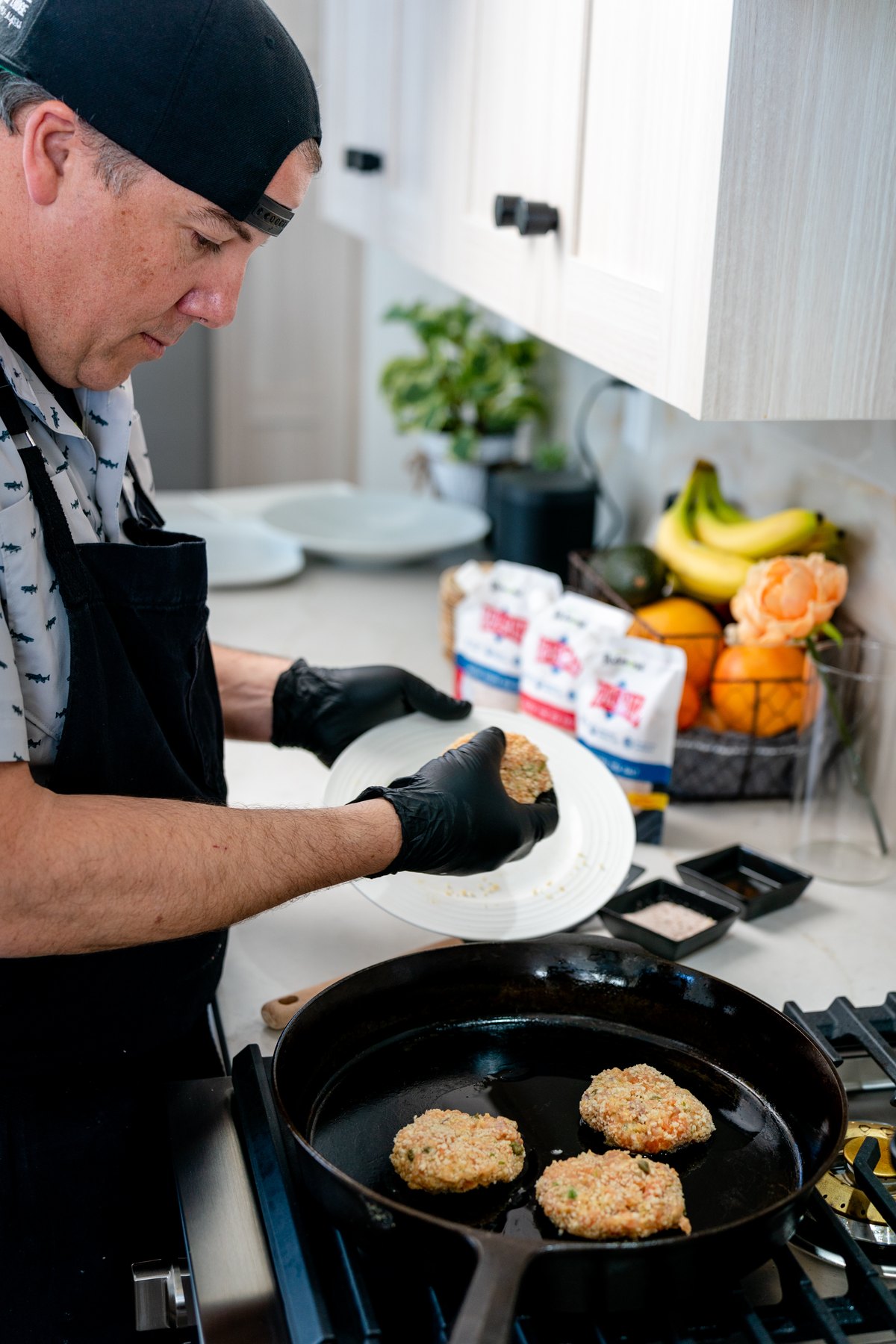 Laying a panko coated salmon cake into a hot cast iron skillet