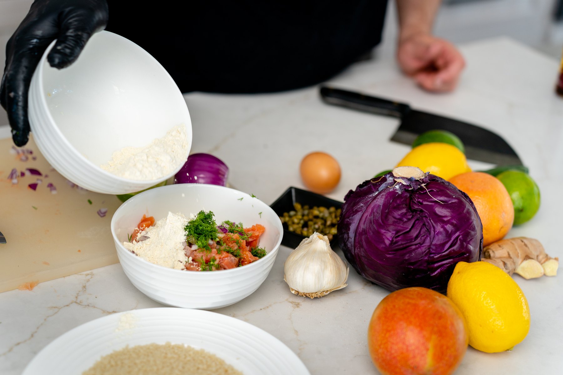 Pouring panko breadcrumbs into a bowl of seasoned chopped salmon