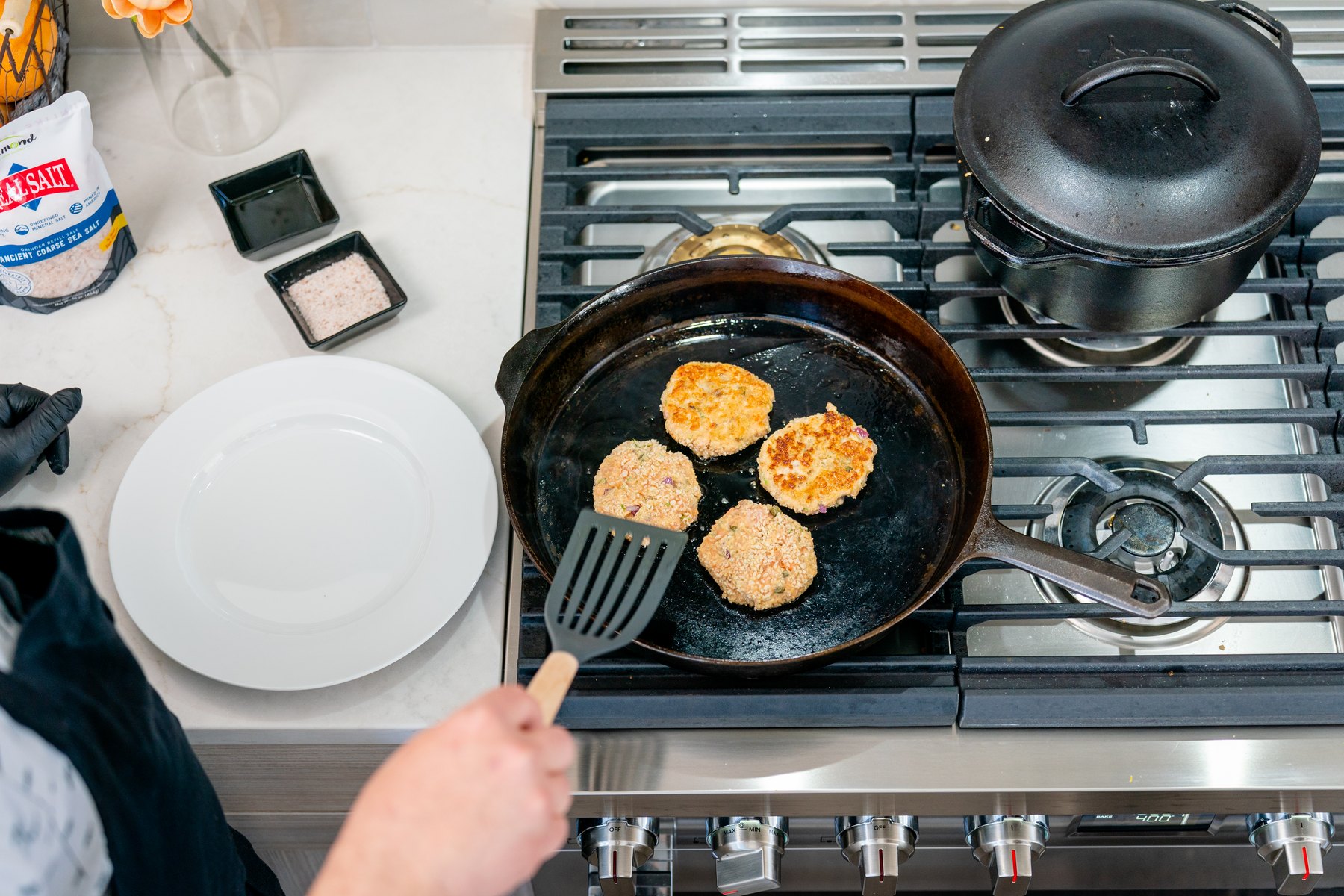 Overhead view of golden salmon cakes frying in a cast iron skillet