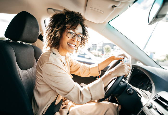 Woman driving her car, smiling as she booked parking in advance. 
