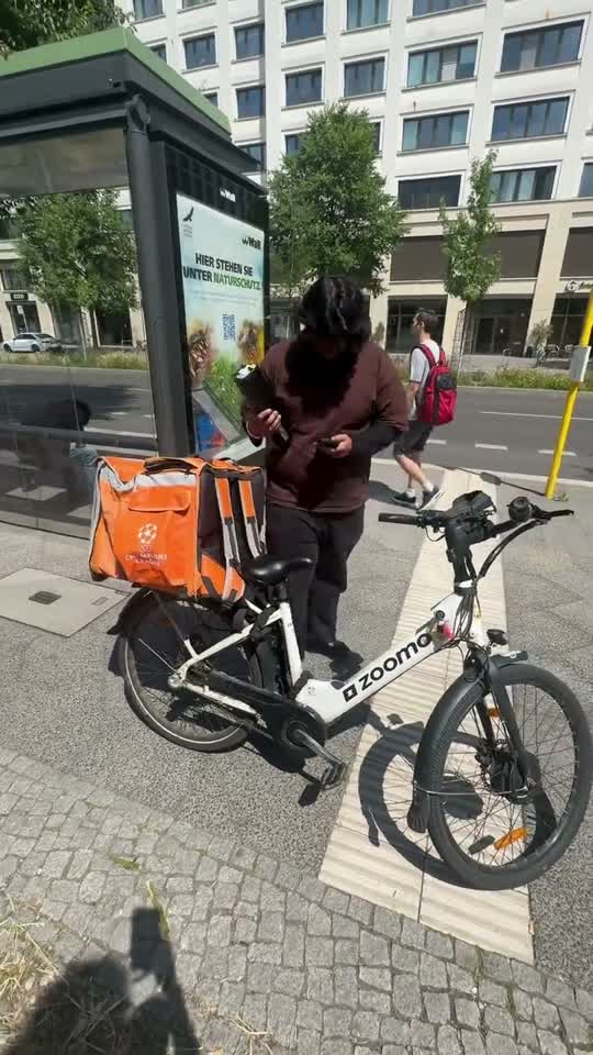 A Zoomo rider parks next to a PowerShelter locker station on a Berlin street.