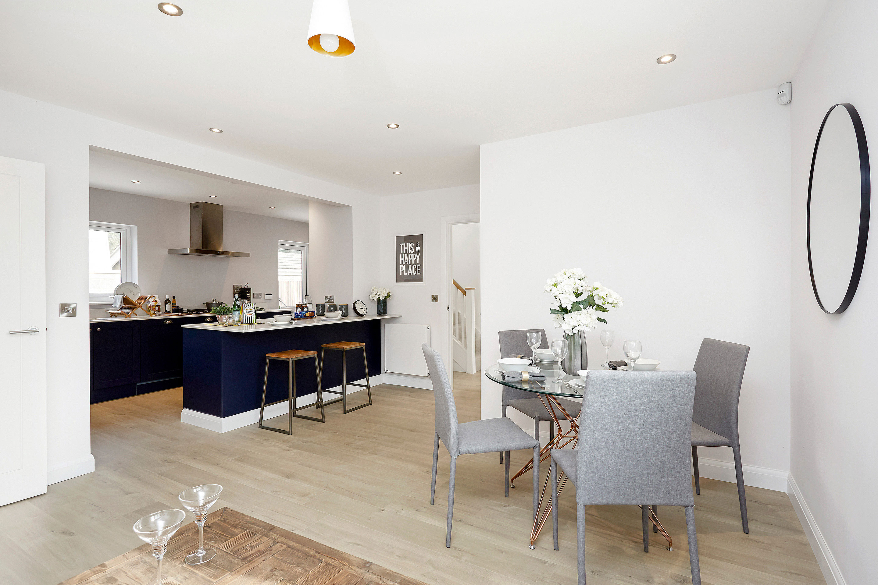 Wide angle view of kitchen and breakfast bar and circular dining table with fresh flowers