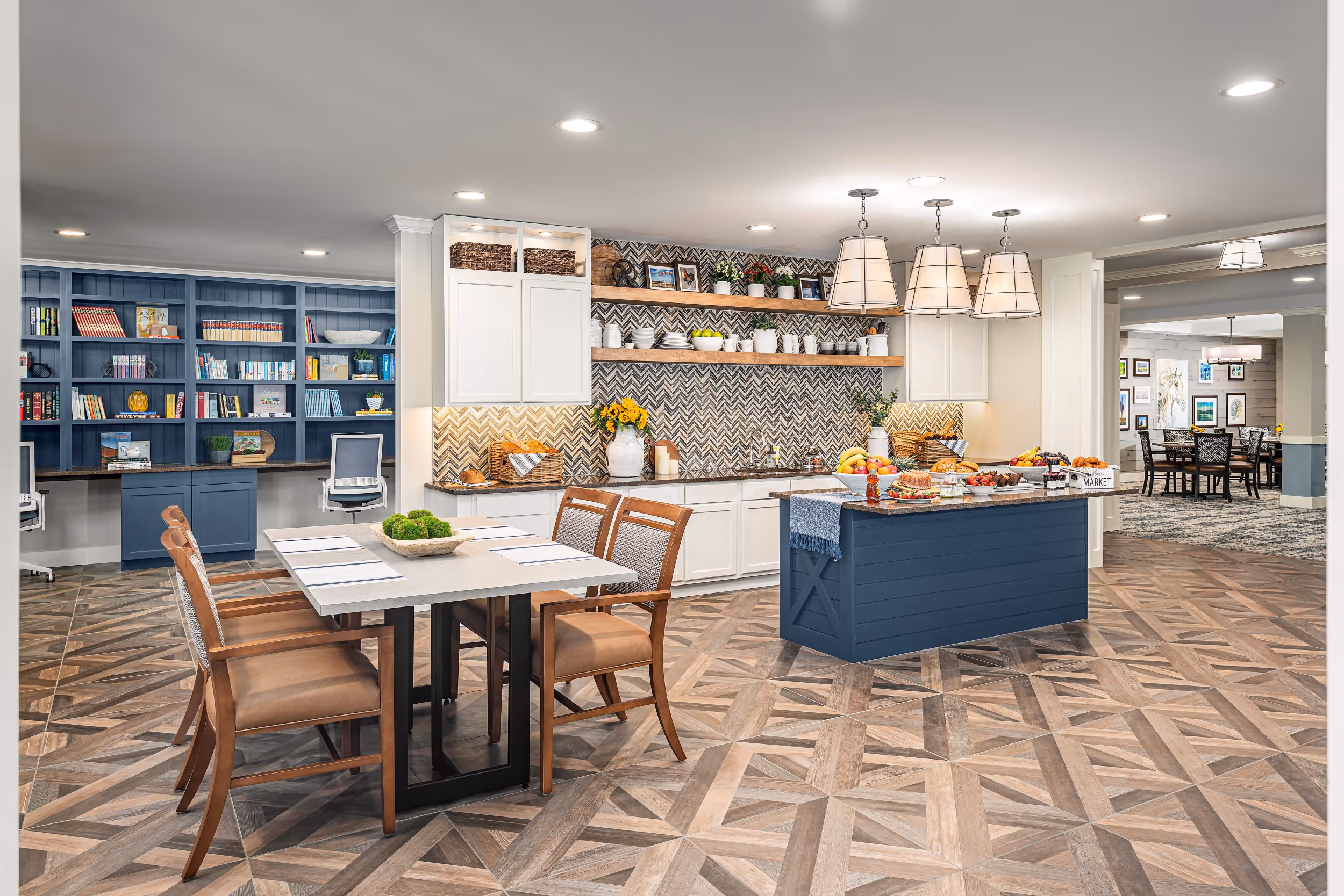 Bright kitchen and dining area with blue island, white cabinets, geometric wood-patterned floor, wooden dining table with four chairs, and built-in blue bookshelves.