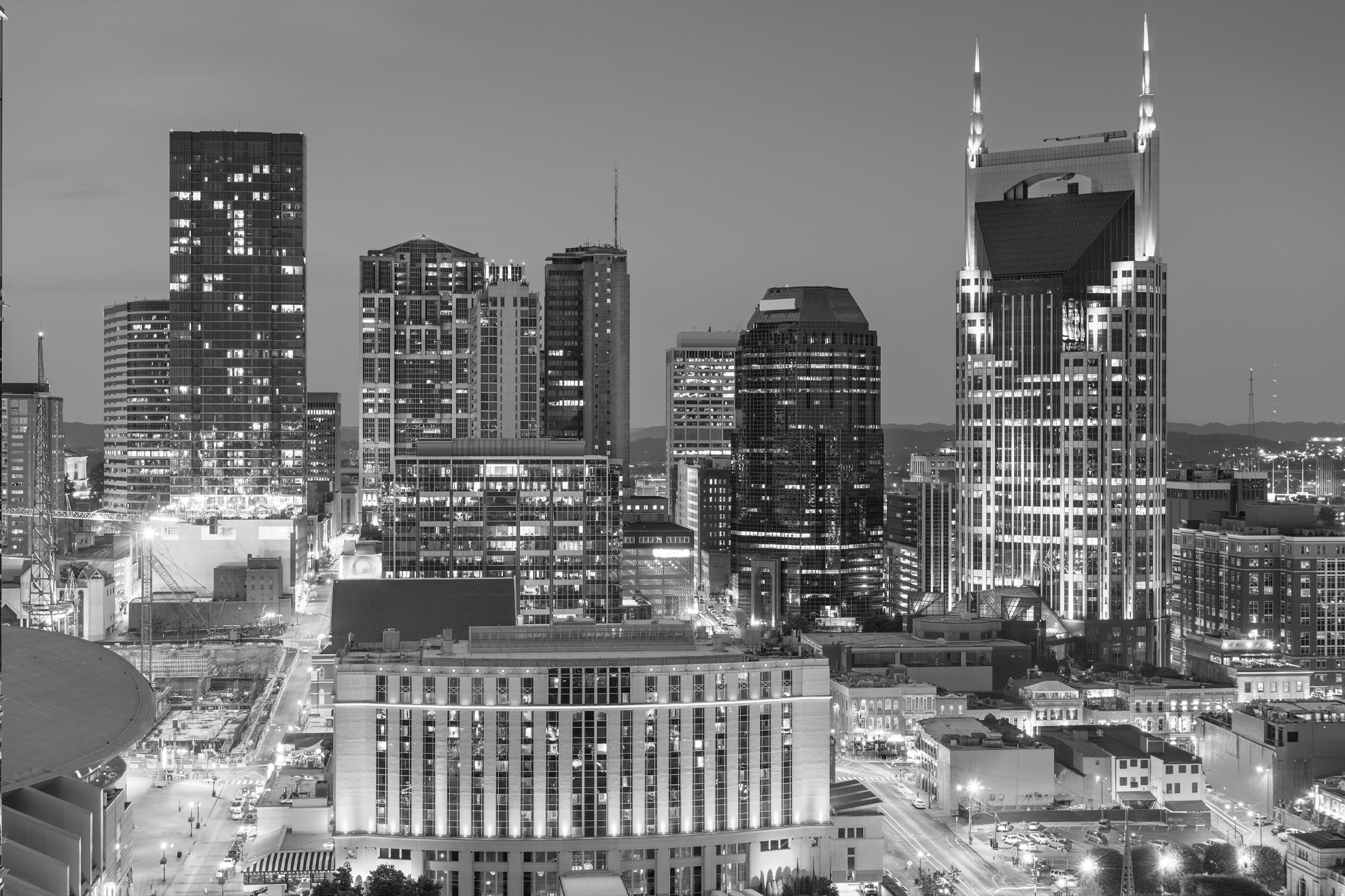 Nighttime cityscape of downtown Nashville with illuminated skyscrapers and streets.