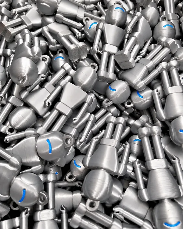 Lote de pequeños robots plateados impresos en 3D en producción seriada