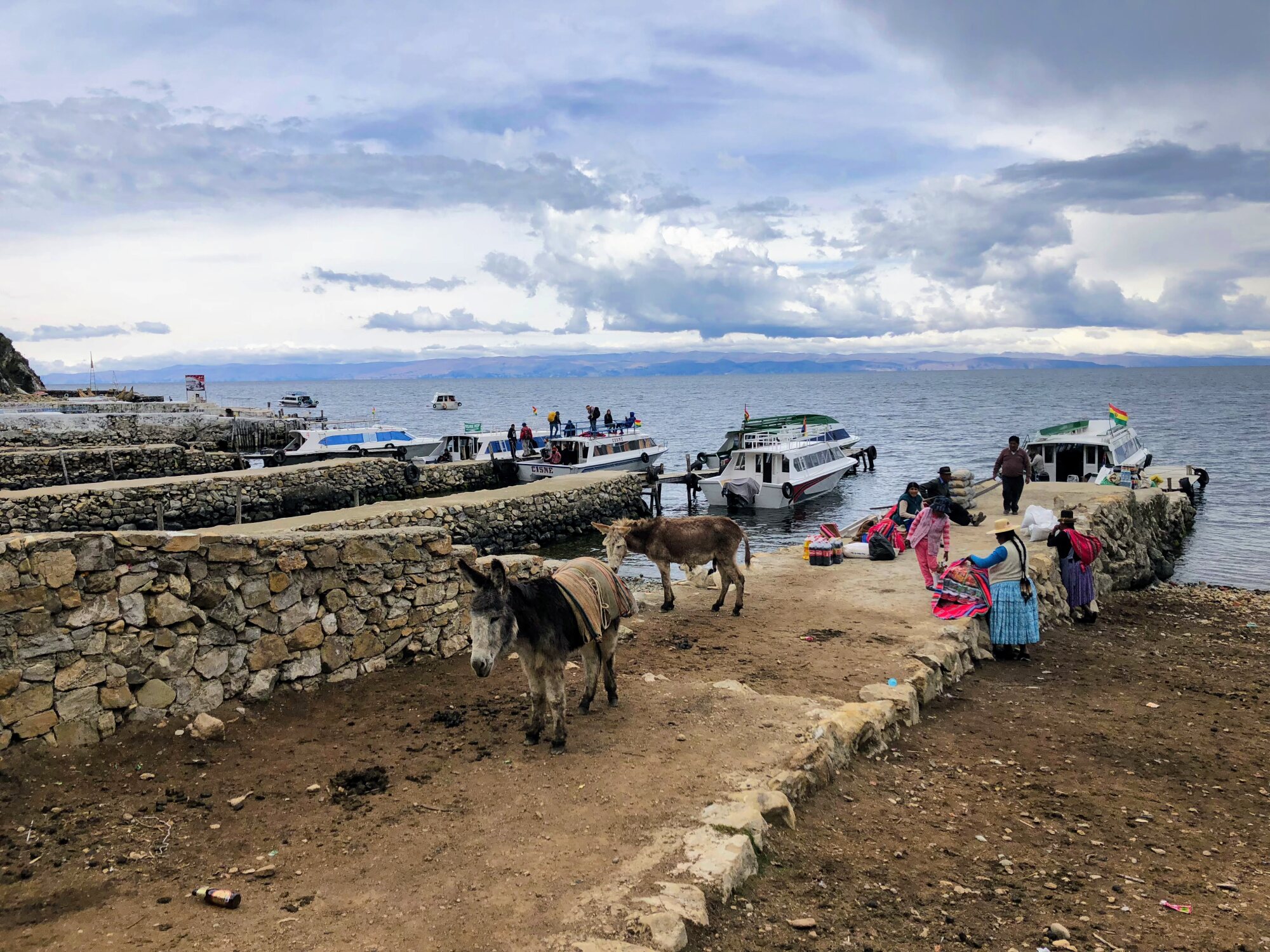 Boats, donkeys and local women at the harbour on Isla del Sol, Lake Titicaca, Bolivia.