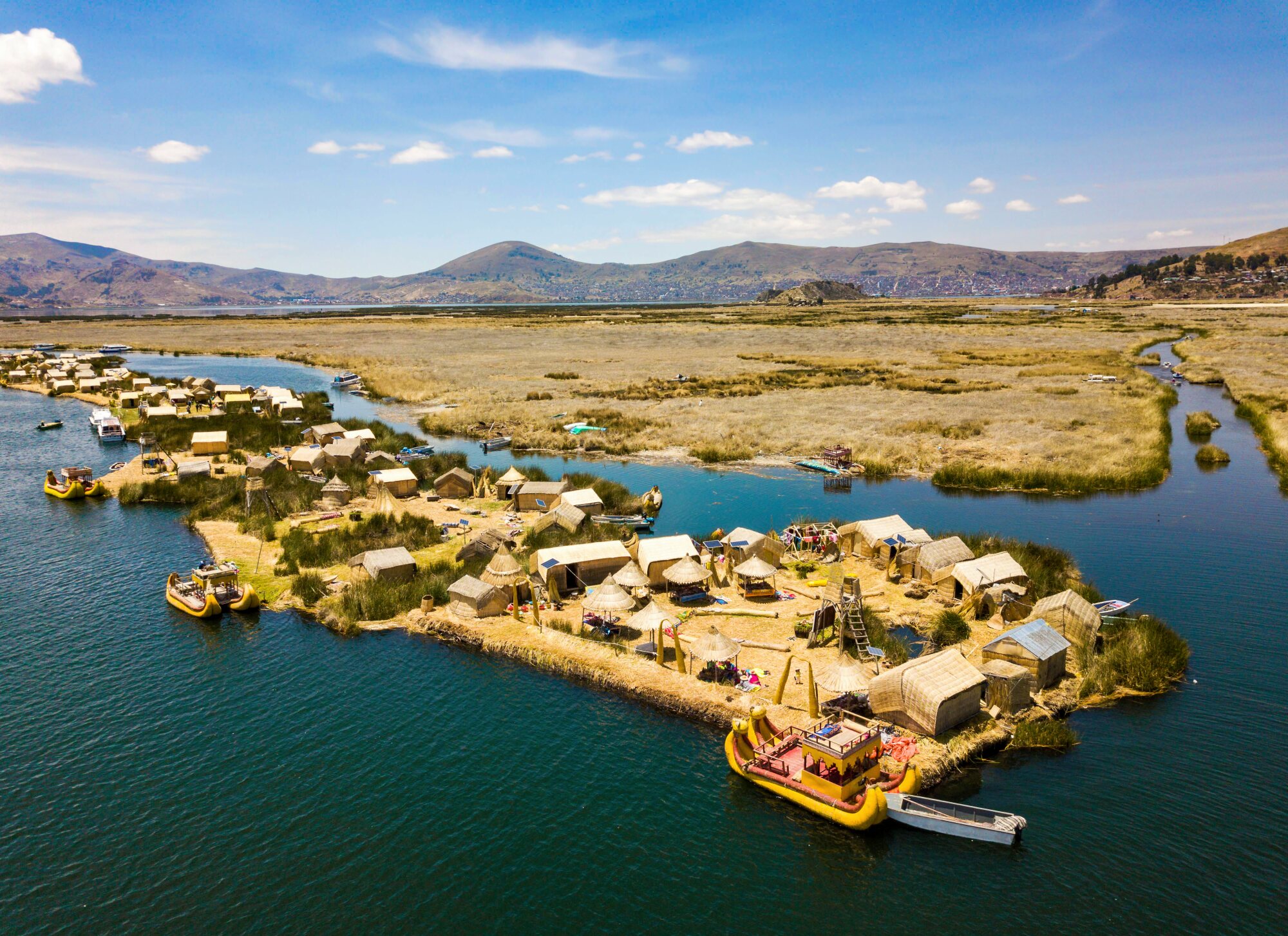 Aerial view of the Uros floating islands, reed houses and traditional boats on Lake Titicaca near Puno, Peru.