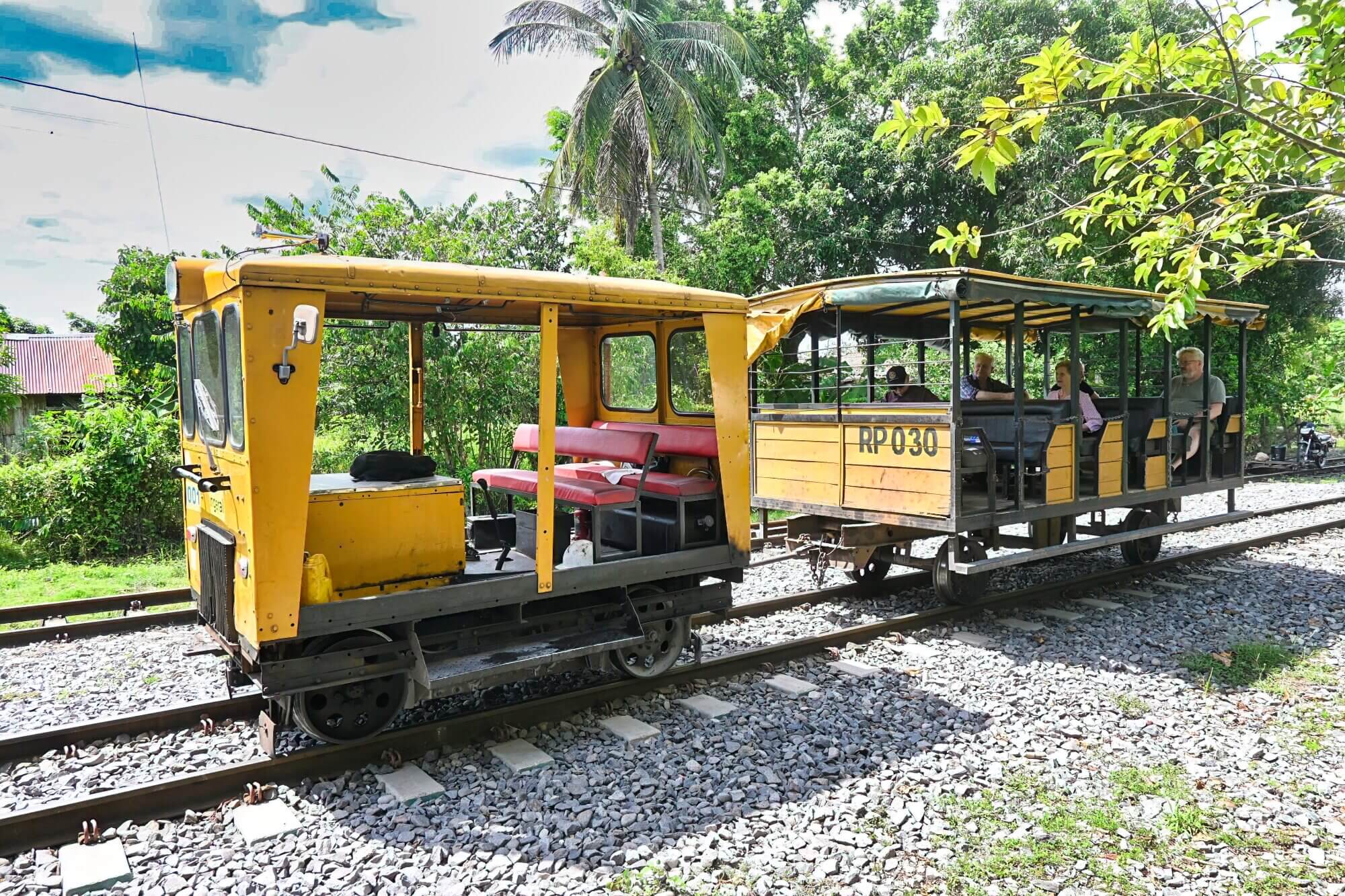 Small local railway vehicle carrying passengers through the tropical Magdalena Valley in Colombia.