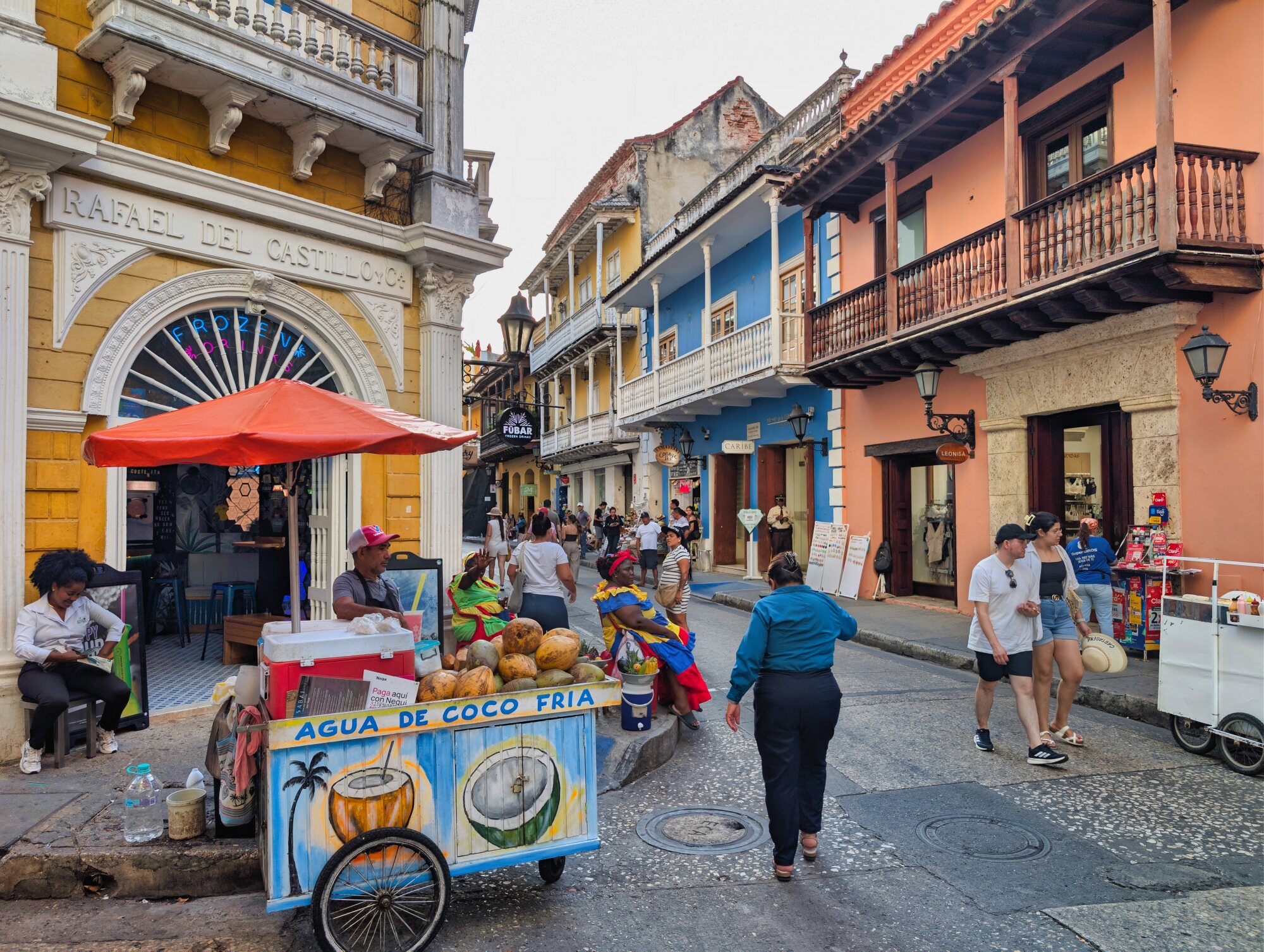 Busy street in Cartagena’s walled city with colorful colonial balconies, vendors and pedestrians.