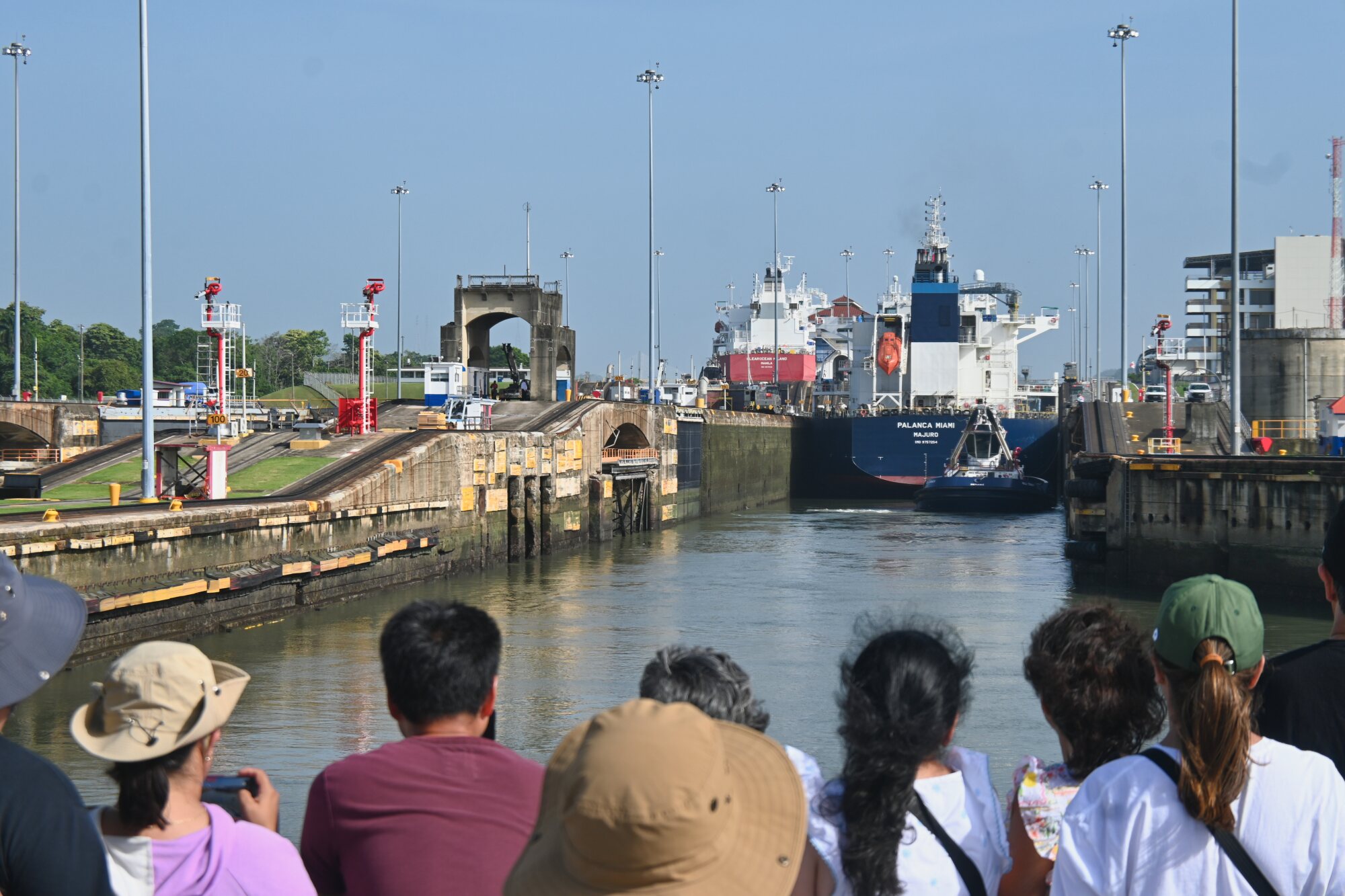 Passengers aboard a tour boat watching a large ship pass through a lock chamber in the Panama Canal.