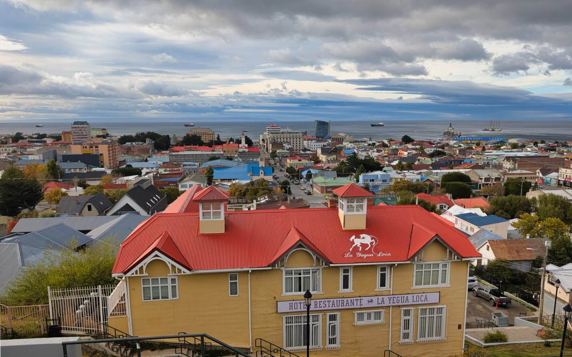 View across Punta Arenas toward the Strait of Magellan with ships offshore in southern Chile.