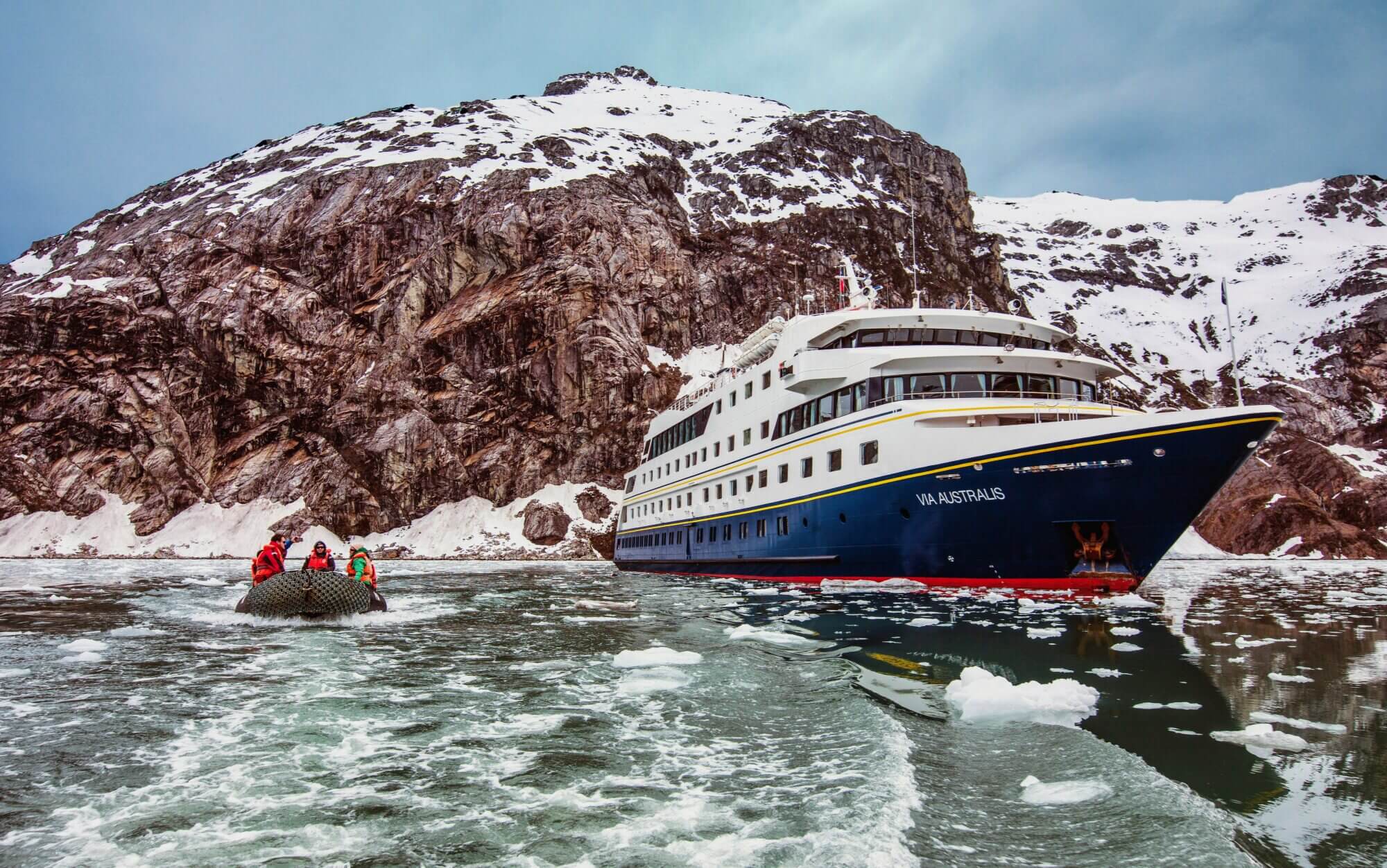 Via Australis expedition ship with a Zodiac in icy waters among the fjords of Tierra del Fuego.