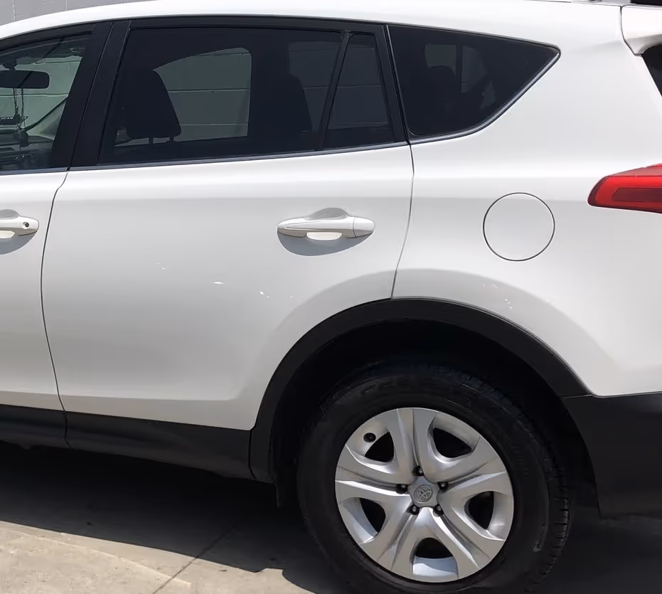 Close-up side view of a white SUV door and rear wheel with silver alloy rim and black tire.