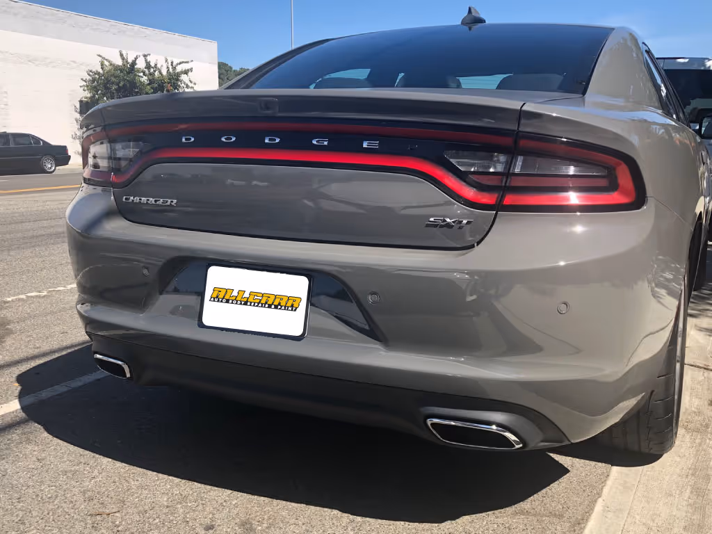 Rear view of a gray Dodge Charger SXT parked on a street, showing its tail lights and dual exhaust.