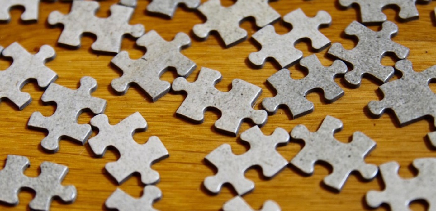 Grey puzzle pieces on wooden background