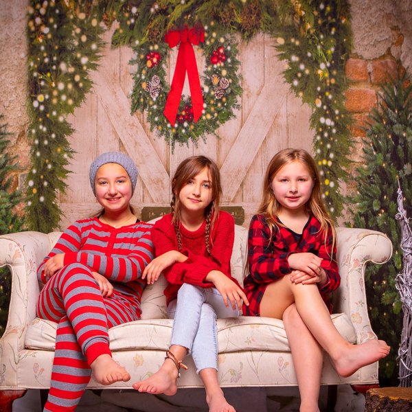 Three girls in holiday outfits on a sofa in front of the barn-door set