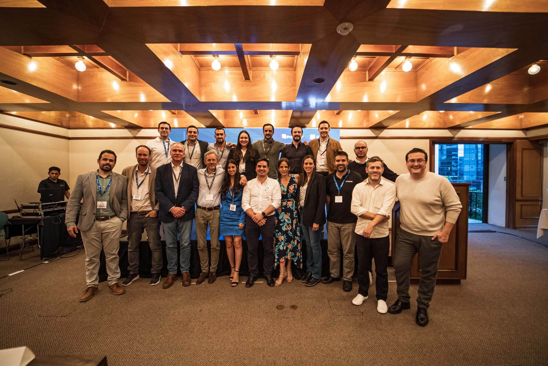 Architect adjusting a detailed wooden architectural scale model of a multi-story building surrounded by trees and smaller houses on a table.