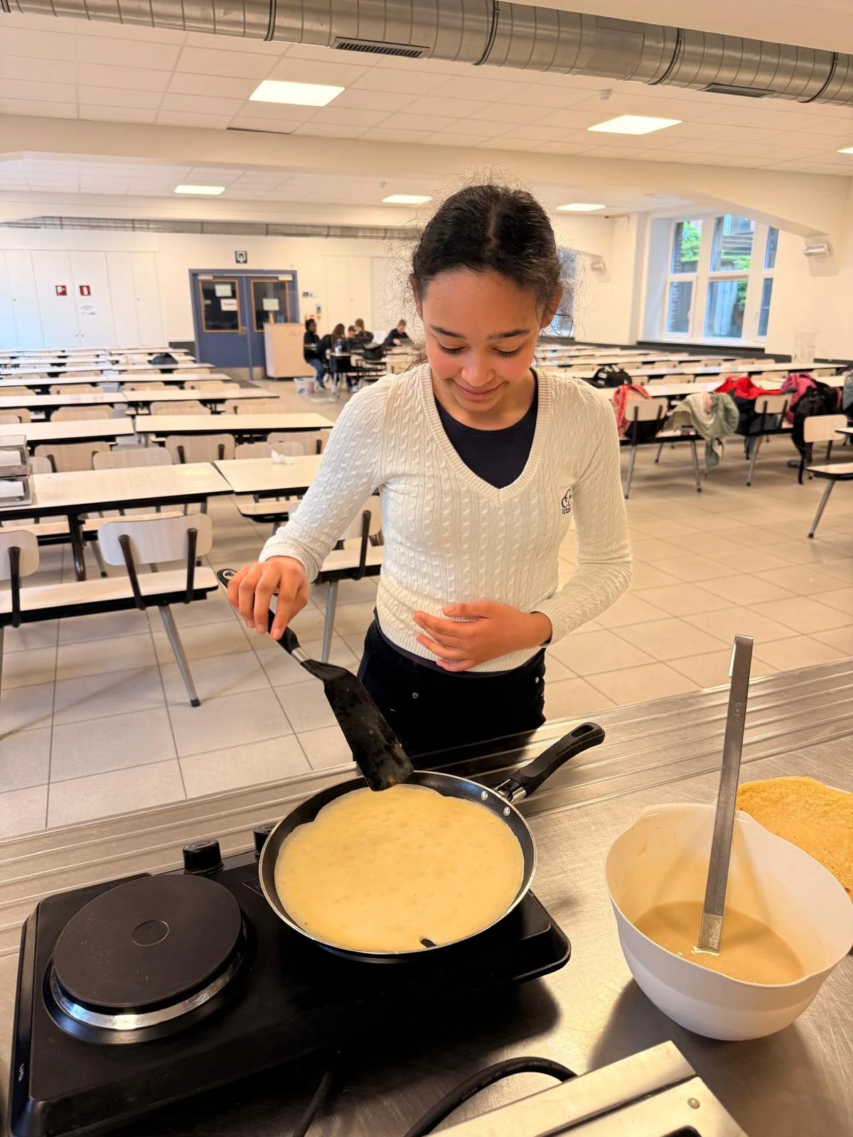 Leerling bakt pannenkoeken in de refter van RC Internaat
