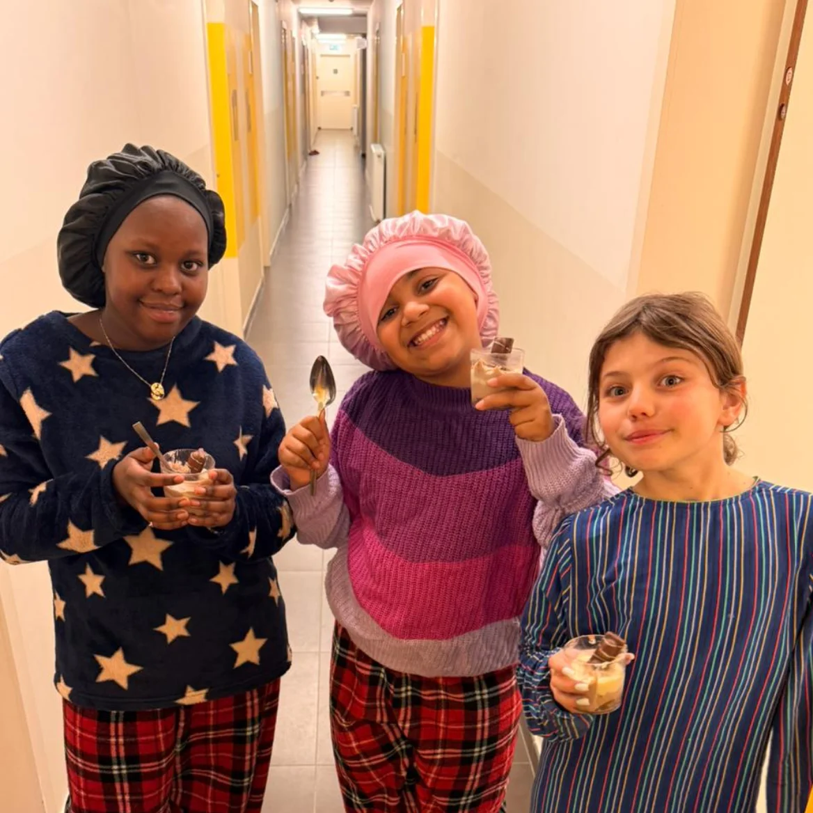 Drie leerlingen in pyjama genieten van een dessert op RC Internaat