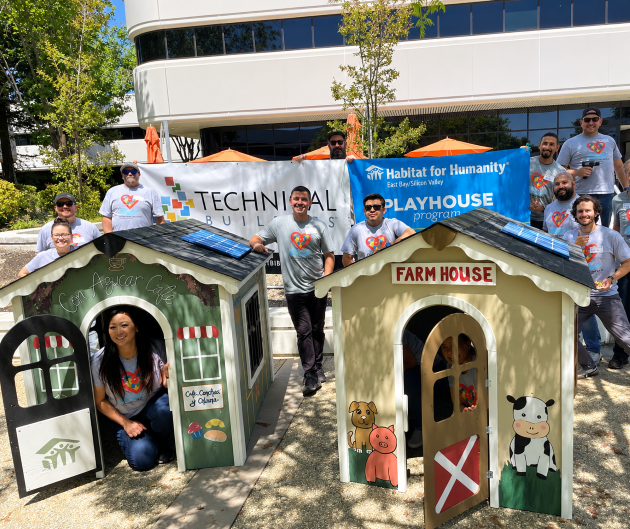Technical Builders employees posing in and around two playhouses that they built to donate to Habitat for Humanity in front of their office in San Jose, CA 