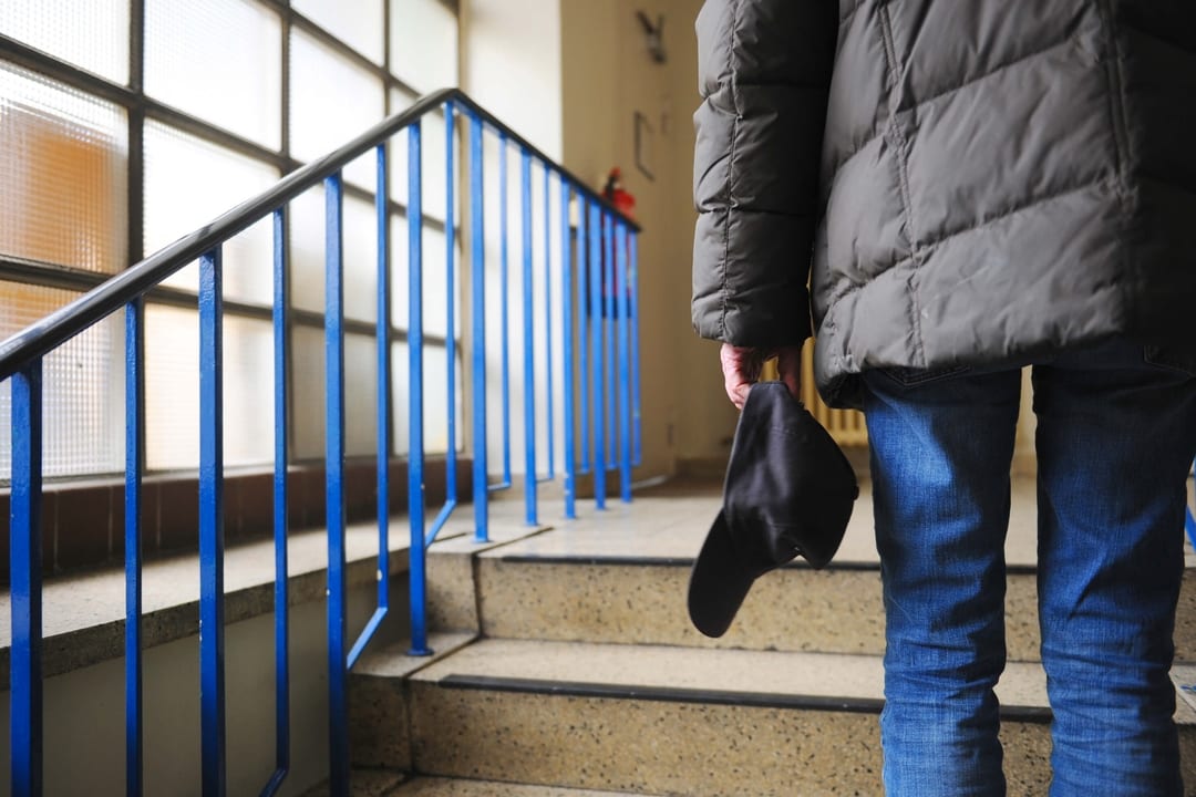 Obdachloser Mann auf der Treppe in der Einrichtung des Berliner Wohnforums