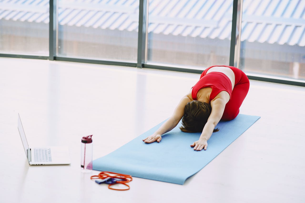 a lady practicing the child's pose on a yoga mat