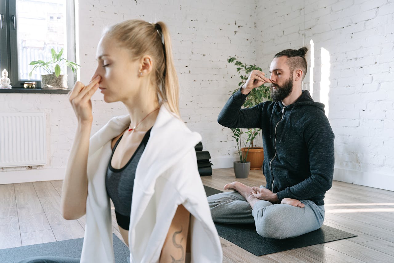 a man and a woman in a yoga studio performing alternate nostril breathing