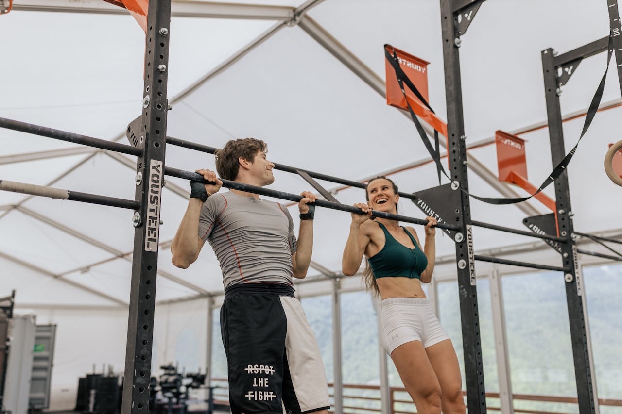 a man and a woman doing pull-ups at the gym
