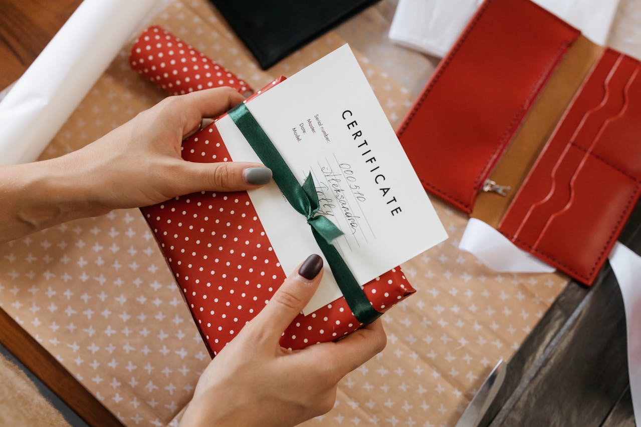 a woman holding a certificate and a gift, wrapped under a decorative bow