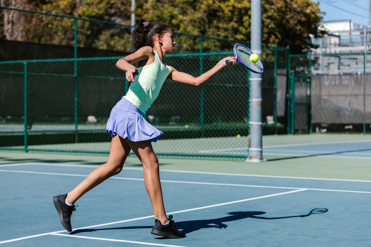a young girl practicing tennis on a court