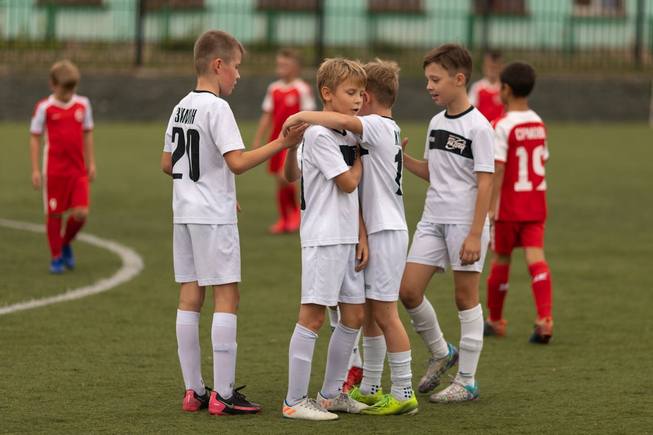 a group of young boys hugging during a football game 