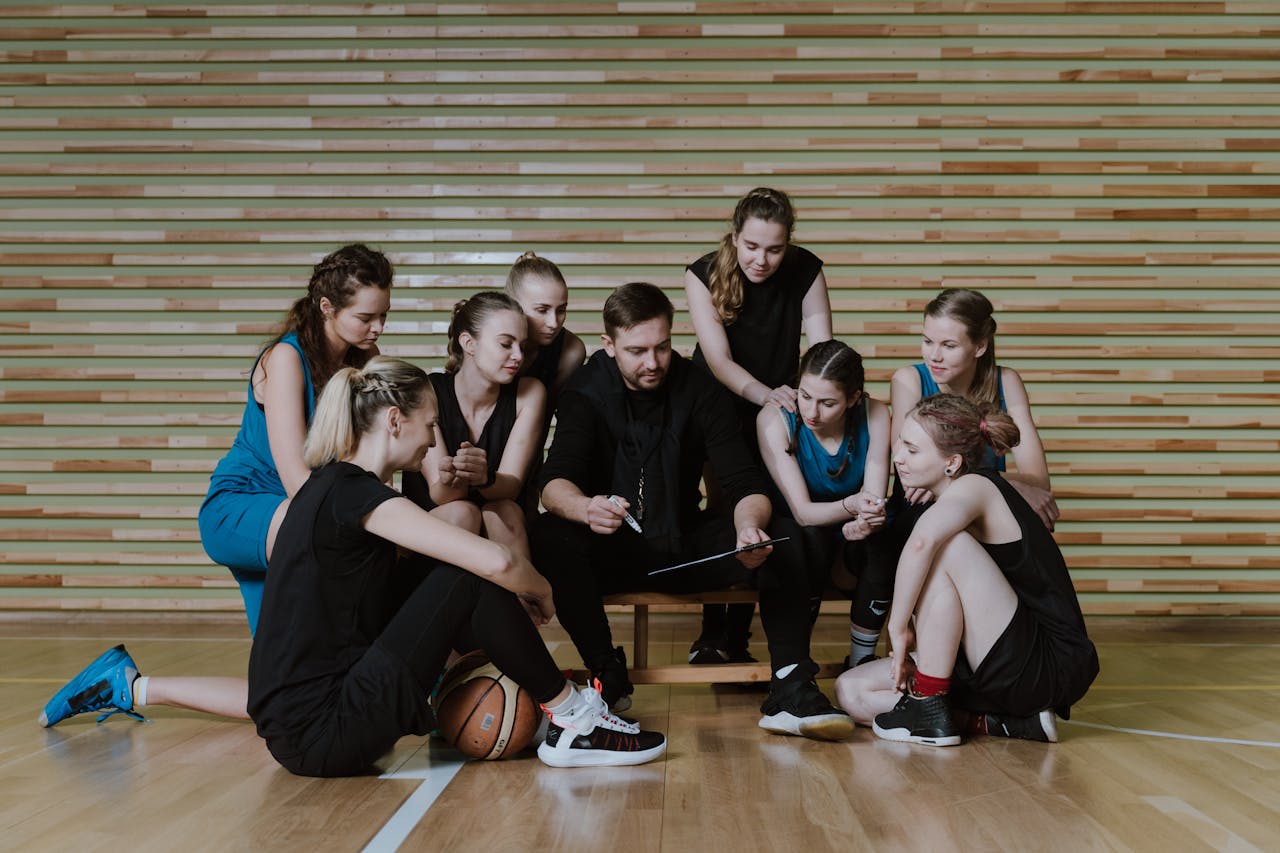 a basketball coach having a conversation with his team on the court