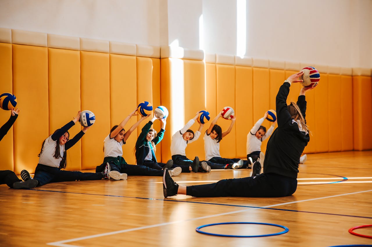 a volleyball coach performing a drill alongside a bunch of students on a court