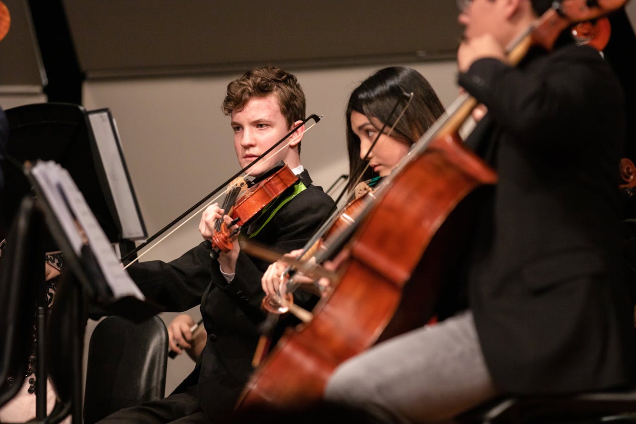 three music students playing the violin at a music recital