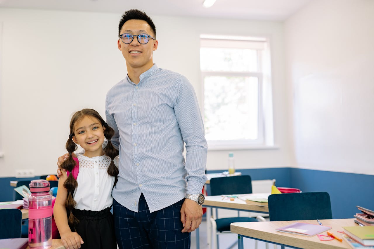 a teacher and a young student posing for a photograph in a classroom