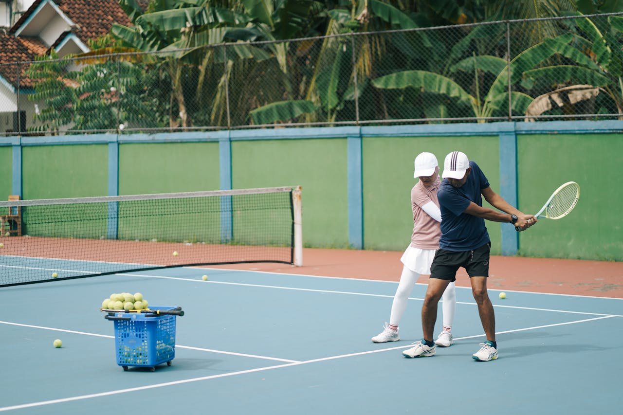 a tennis coach and student practising tennis drills on a court surrounded by trees