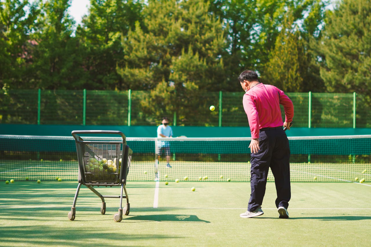 a coach throwing tennis balls across the net to train a tennis player