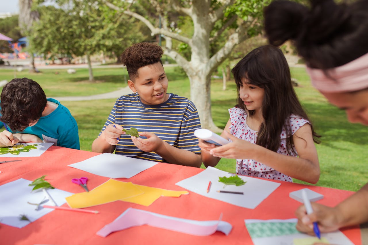 a bunch of kids doing arts and crafts in a park at a summer camp