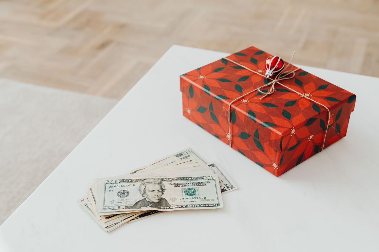 a wrapped gift and some money bills on a white table